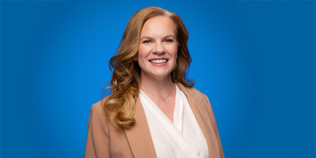 A person smiles while she holds a blue framed picture.