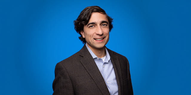 A person in a suit and tie smiles.